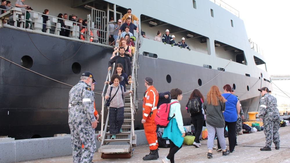 This handout photo taken on January 4, 2020 and received from the Australian Department of Defence shows evacuees (C) disembarking from MV Sycamore at Bluescope Wharf in Hastings, Victoria state. Up t