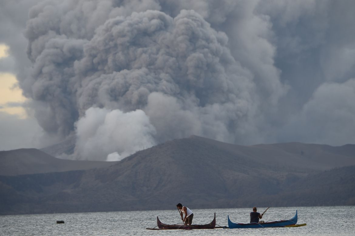 Residents living along Taal lake catch fish as Taal volcano erupts in Tanauan town, Batangas province south of Manila on January 14, 2020. - Taal volcano in the Philippines could spew lava and ash for