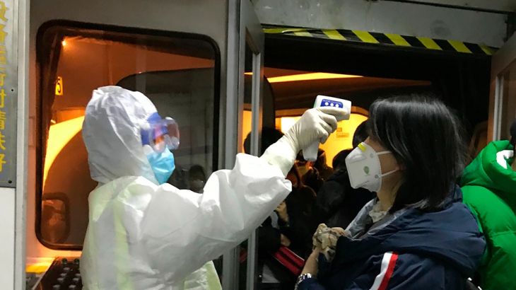 Health Officials in hazmat suits check body temperatures of passengers arriving from the city of Wuhan Wednesday, Jan. 22, 2020, at the airport in Beijing, China. Nearly two decades after the disastro