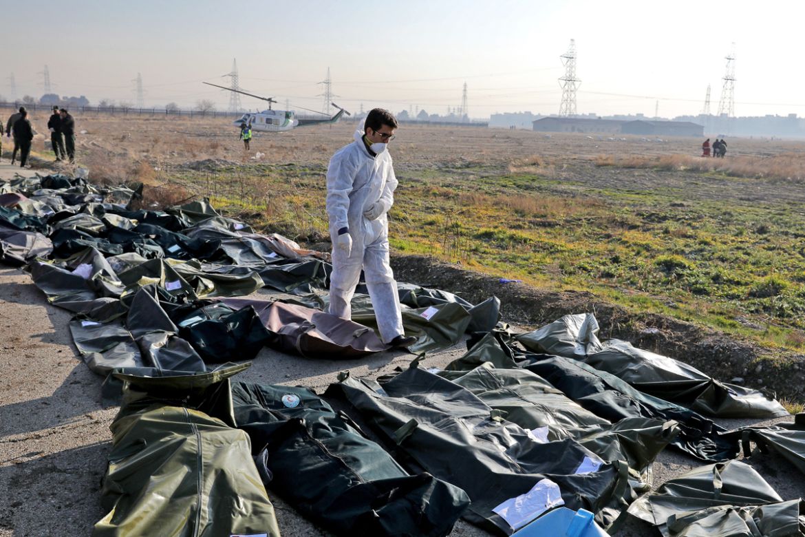 A forensic investigator works at the scene of a Ukrainian plane crash as bodies of the victims are collected, in Shahedshahr, southwest of the capital Tehran, Iran, Wednesday, Jan. 8, 2020. A Ukrainia