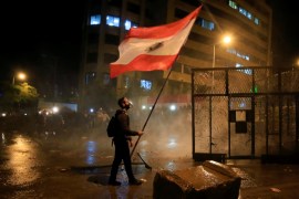 A demonstrator holds the Lebanese flag during a protest against the newly formed government outside the government headquarters in downtown Beirut on January 25, 2020 [Reuteres/Ali Hashisho]