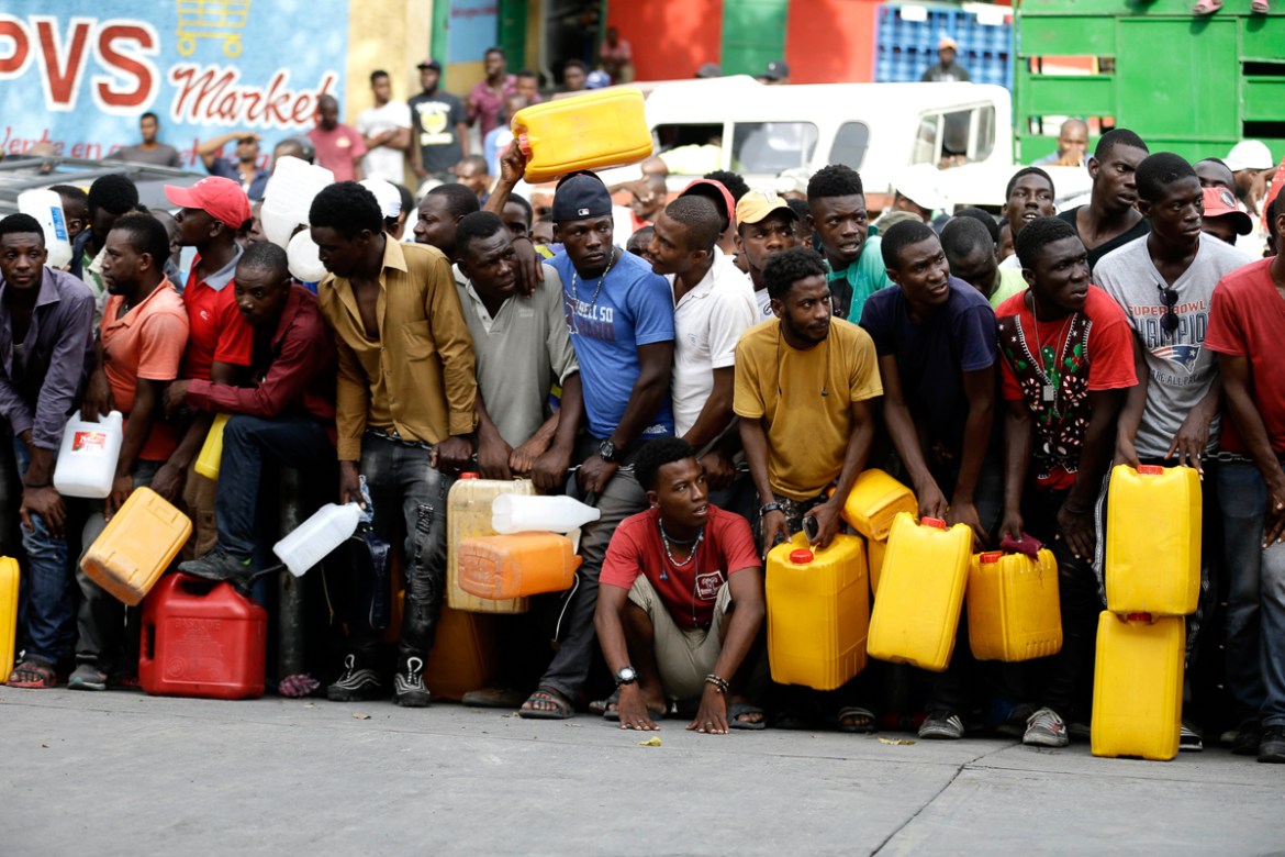 People gather at a closed gas station, hoping it will open eventually, during a fuel shortage in Port-au-Prince, Haiti, Wednesday, Sept. 4, 2019. Stations have been reducing their operating hours for