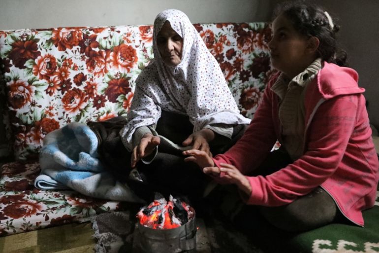 A displaced family warm up their hands at an unfinished apartment in Tripoli