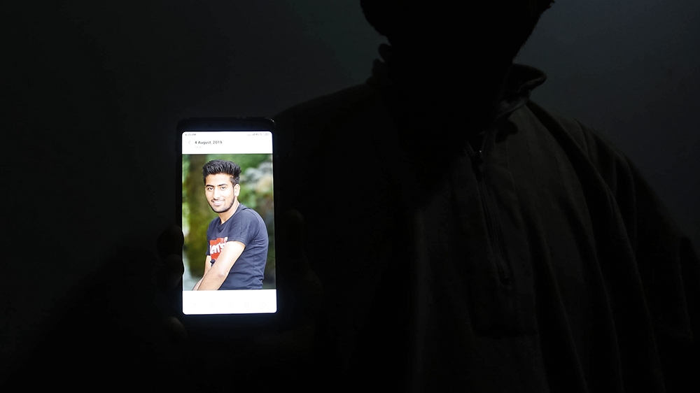 Suhail Marazi, 26, brother of Osaib Altaf Marazi displaying his picture from his phone at their home in Palpora, New Colony. [Shuaib Bashir/Al Jazeera]