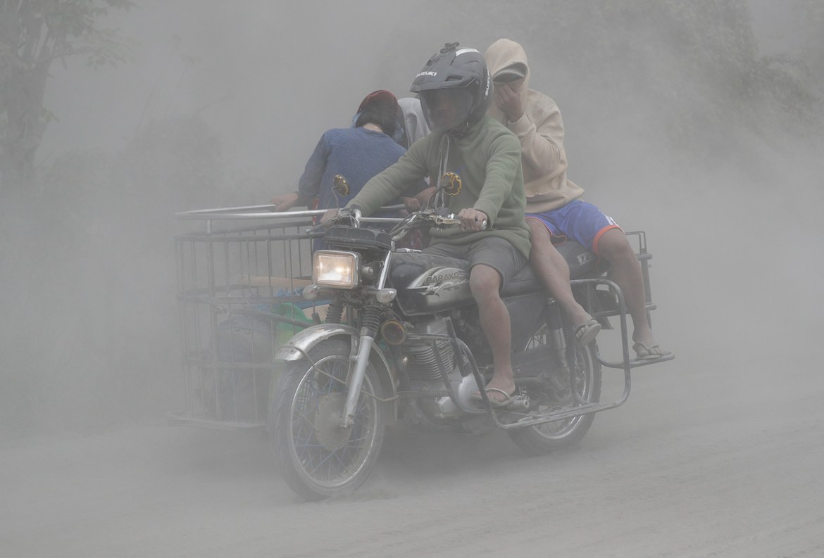 A family rides their motorcycle through clouds of ash as they evacuate to safer grounds as Taal volcano in Tagaytay, Cavite province, southern Philippines on Monday, Jan. 13, 2020. Red-hot lava is gus