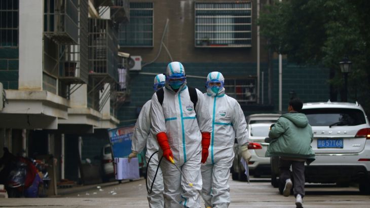 Workers from local disease control and prevention department in protective suits disinfect a residential area following the outbreak of a new coronavirus, in Ruichang, Jiangxi province, China January