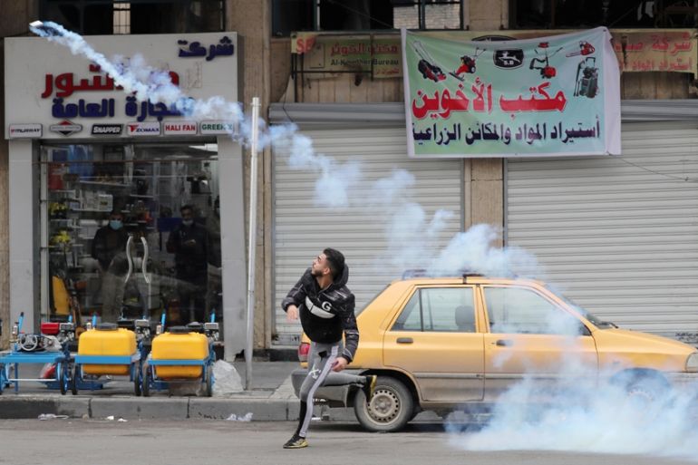 A demonstrator throws a tear gas canister back at the Iraqi security forces during ongoing anti-government protests in Baghdad, Iraq January 25, 2020. REUTERS/Thaier al-Sudani