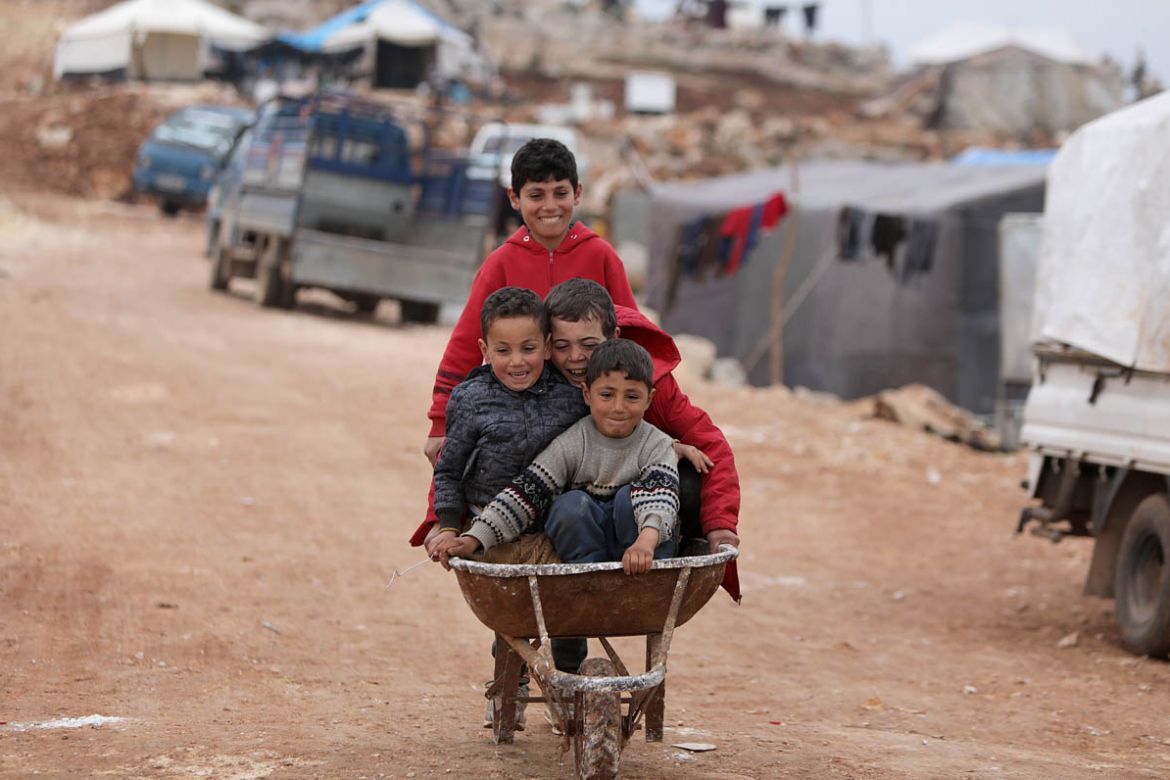 Syrian children play at a makeshift camp for displaced people who fled pro-regime forces attacks in the Idlib and Aleppo provinces, on February 18, 2020 north of the city of Idlib, near the Turkish bo