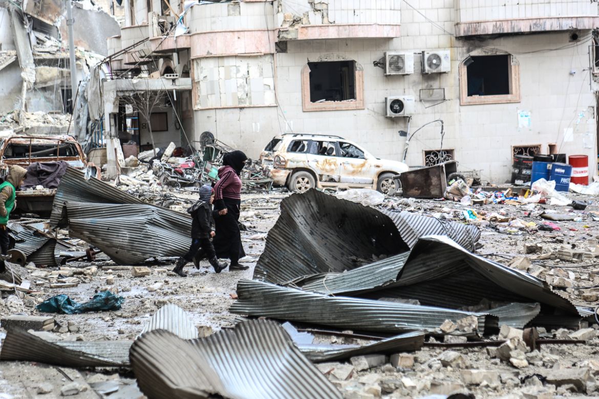 IDLIB, SYRIA - JANUARY 30 : A woman walks with a child outside a hospital near collapsed and damaged buildings after Russian warplanes hit residential areas in Idlib, a de-escalation zone in northwest