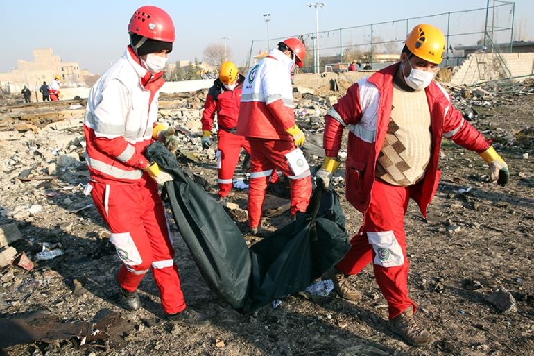 Members of the International Red Crescent collect bodies of victims around the wreckage after an Ukraine International Airlines Boeing 737-800 carrying 176 people crashed near Imam Khomeini Airport in