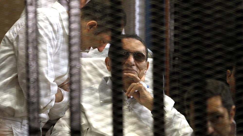 A file photo dated 13 April 2013 shows Gamal Mubarak (L) and brother Alaa Mubarak (R), with their father former Egyptian President Hosni Mubarak in a cage inside the court room during his trial at the