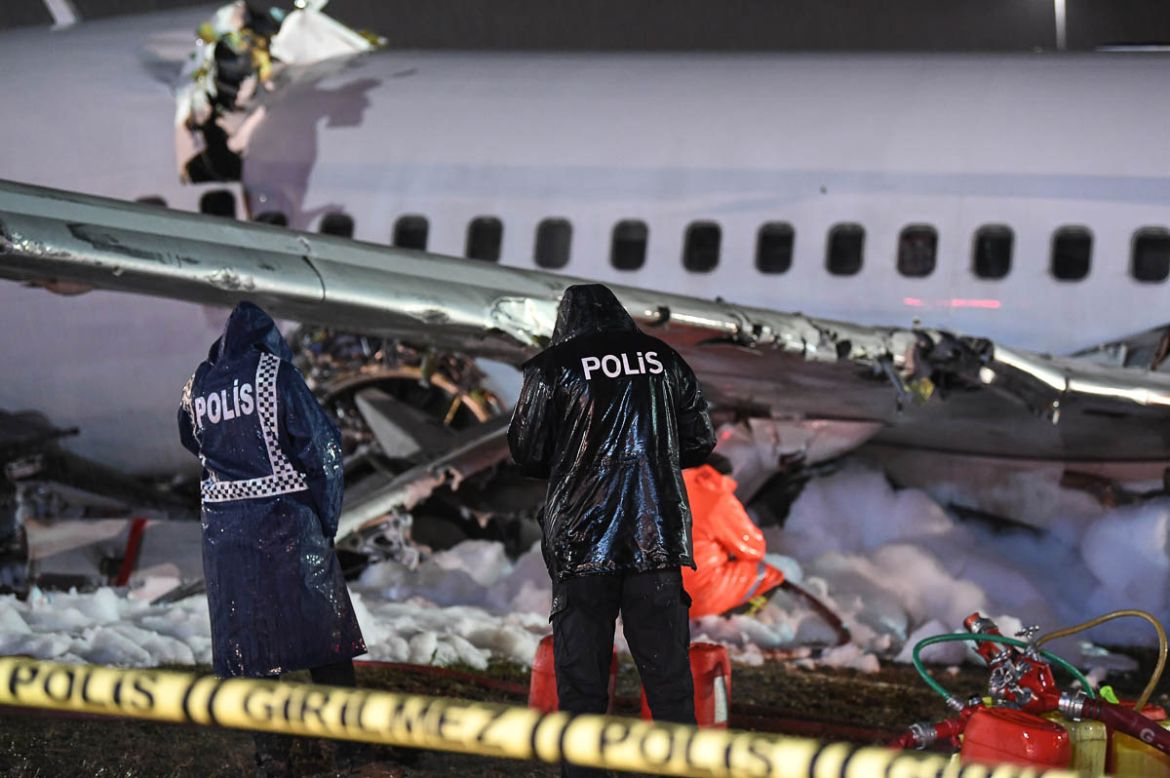 Police officers stand near the site of the crash of a Pegasus Airlines Boeing 737 airplane, after it skidded off the runway upon landing at Sabiha Gokcen airport in Istanbul on February 5, 2020. - The