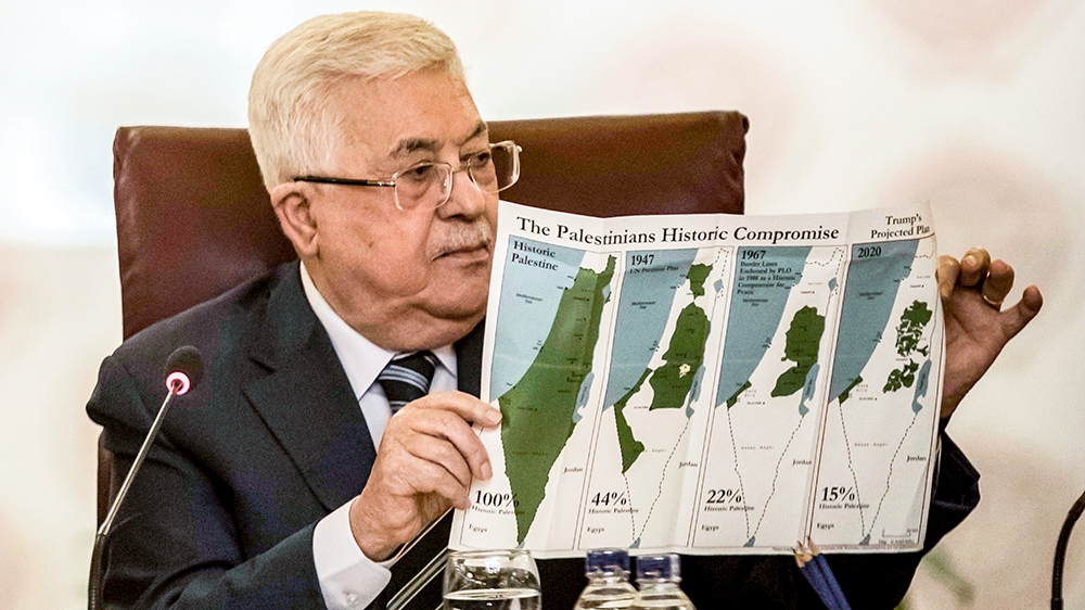 Palestinian president Mahmud Abbas holds a placard showing maps of (L to R) historical Palestine, the 1947 United Nations partition plan on Palestine, the 1948-1967 borders between the Palestinian ter