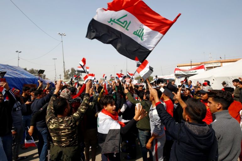 Iraqi demonstrators hold the Iraqi flag as they chant slogans during ongoing anti-government protests in Najaf