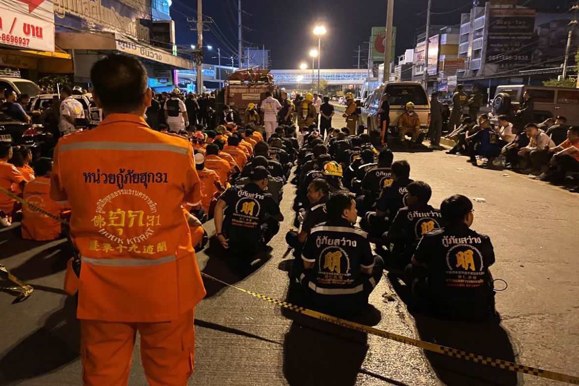 Rescue workers sit outside the Terminal 21 mall, where a mass shooting took place and the gunman is currently still hiding, in the Thai northeastern city of Nakhon Ratchasima on February 9, 2020. - A