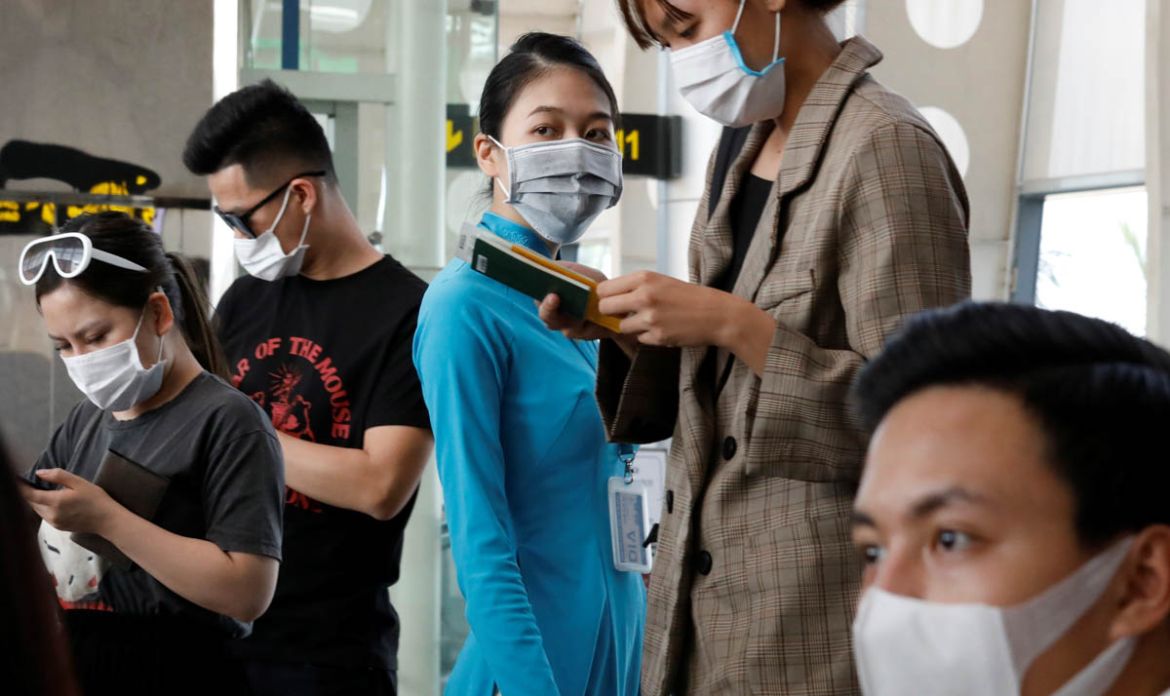 A ground staff member of Vietnam Airlines and passengers wearing protective mask, following an outbreak of the novel coronavirus, wait for boarding at the Danang airport in Danang city, Vietnam Februa