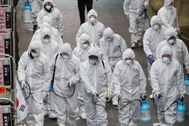 Market workers wearing protective gear spray disinfectant at a market in the southeastern city of Daegu on February 23, 2020 as a preventive measure after the COVID-19 coronavirus outbreak. - South Ko