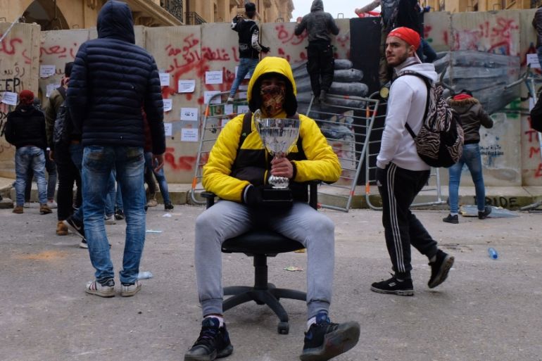 A protester holding a trophy sits in an office chair taken from a nearby bank. "I won," he told Al Jazeera.