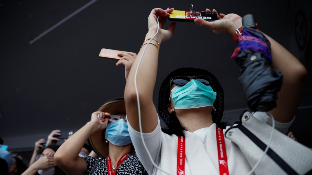Spectators wearing masks in precaution of the coronavirus outbreak watch an aerial display at the Singapore Airshow in Singapore