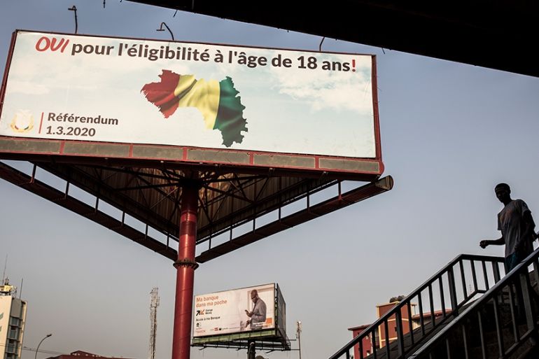A man walks in front of a billboard advertising "Yes" to the referendum in Conakry on February 26, 2020. - On March 1st, 2020 Guinea Conakry will hold a referendum to change the constitution. If succe