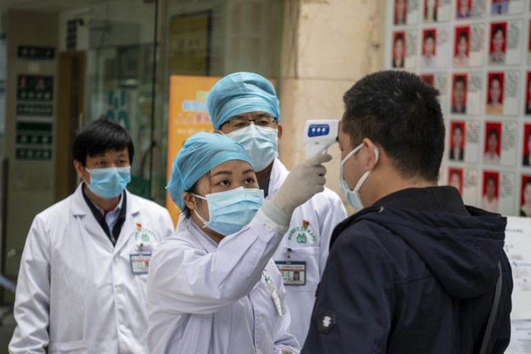 Medical personnel check the body temperature of people entering a community health center and pharmacy in Guangzhou, Guangdong Province, China, 03 February 2020. Wearing masks in metro and all public