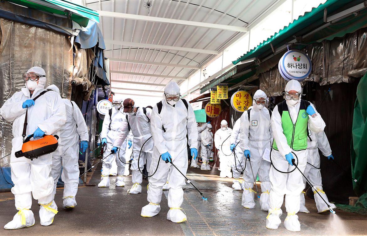 Workers wearing protective suits spray disinfectant as a precaution against the coronavirus at a market in Bupyeong, South Korea, Monday, Feb. 24, 2020. South Korea reported another large jump in new