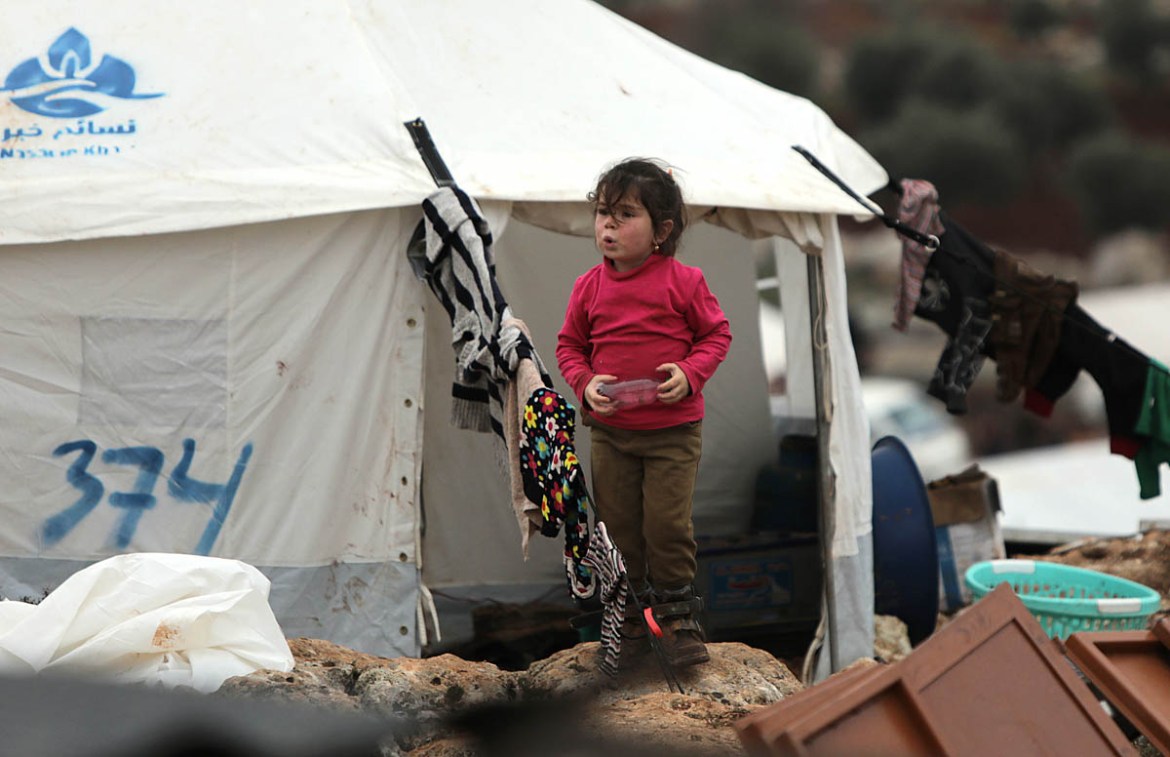 A Syrian girl walks at a makeshift camp for displaced people who fled pro-regime forces attacks in the Idlib and Aleppo provinces, on February 18, 2020 north of the city of Idlib, near the Turkish bor