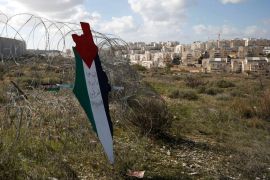 A representation of a map with the colors of the Palestinian flag reading "Jerusalem is the eternal capital of Palestine" is placed on a fence as a Jewish settlement is seen during a protest against t
