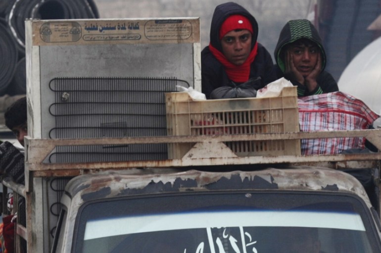 Displaced Syrian boys ride on a truck with belongings in northern Idlib