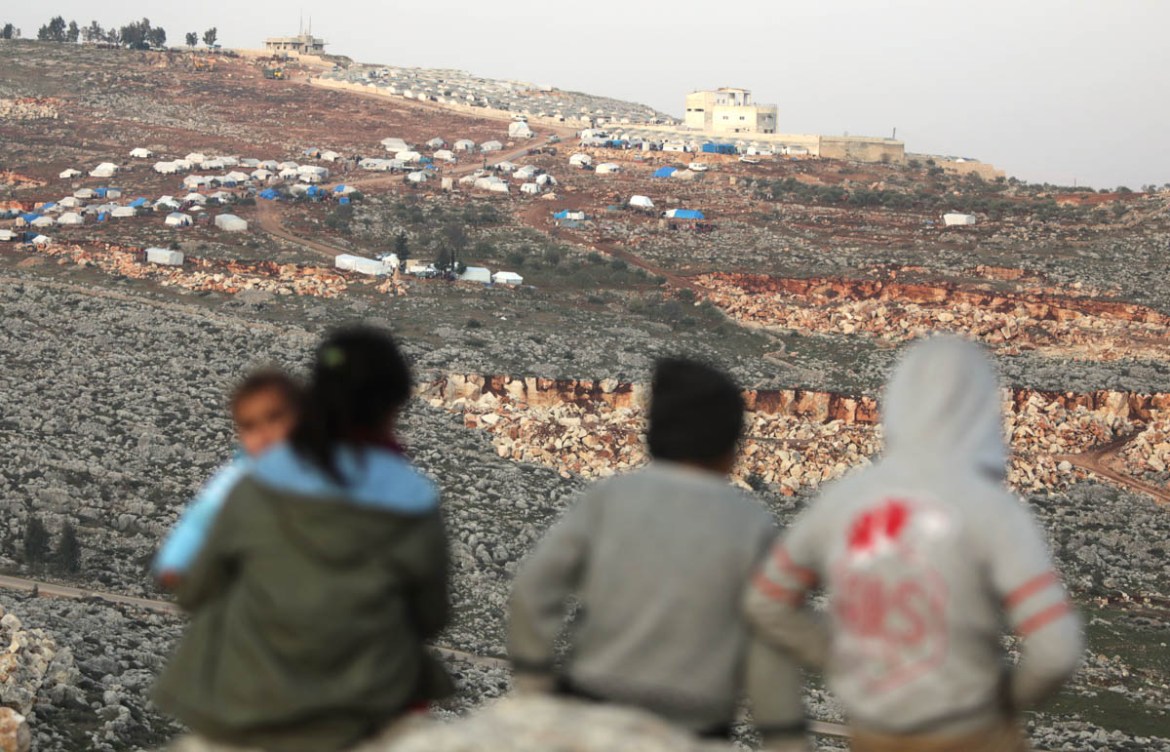 Syrian children watch the horizon from a makeshift camp for displaced people who fled pro-regime forces attacks in the Idlib and Aleppo provinces, on February 18, 2020 north of the city of Idlib, near