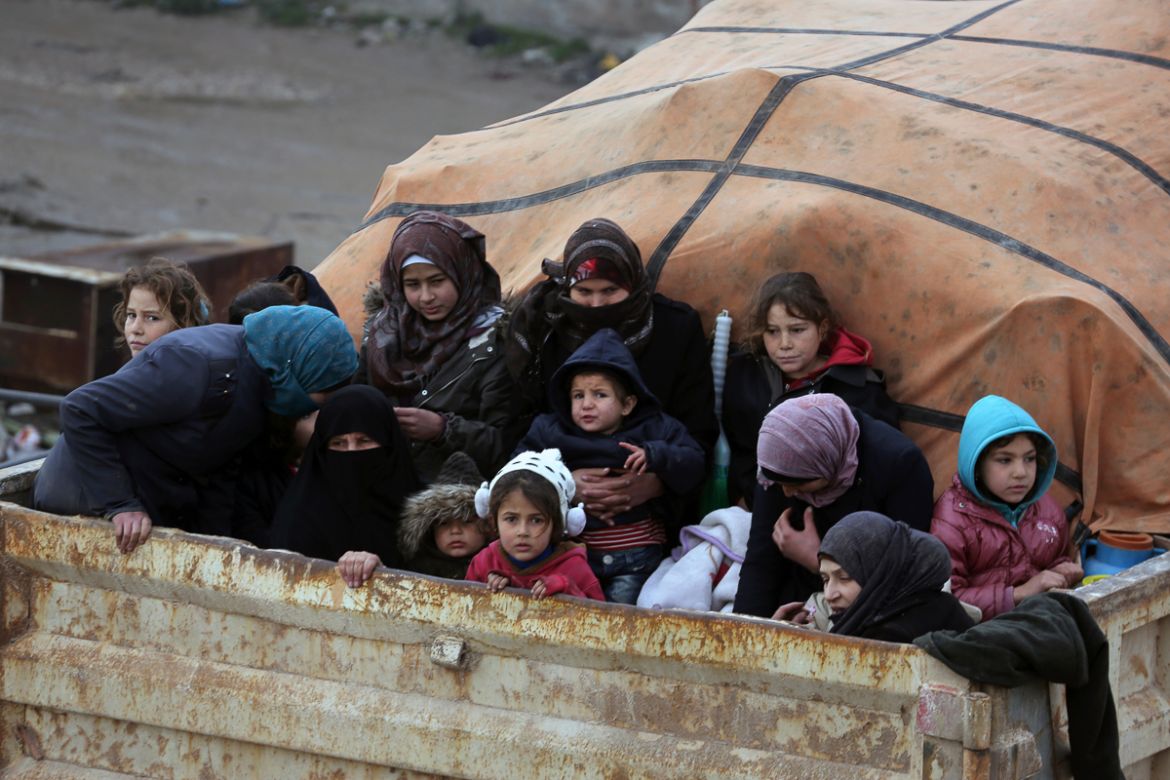 Syrians sit in the back of a truck as they flee the advance of the government forces in the province of Idlib, Syria, towards the Turkish border, Thursday, Jan. 30, 2020. Warplanes struck a town in a
