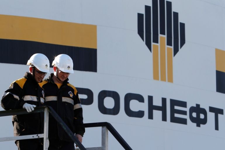 Workers stand next to logo of Russia''s Rosneft oil company at central processing facility of Rosneft-owned Priobskoye oil field outside Nefteyugansk