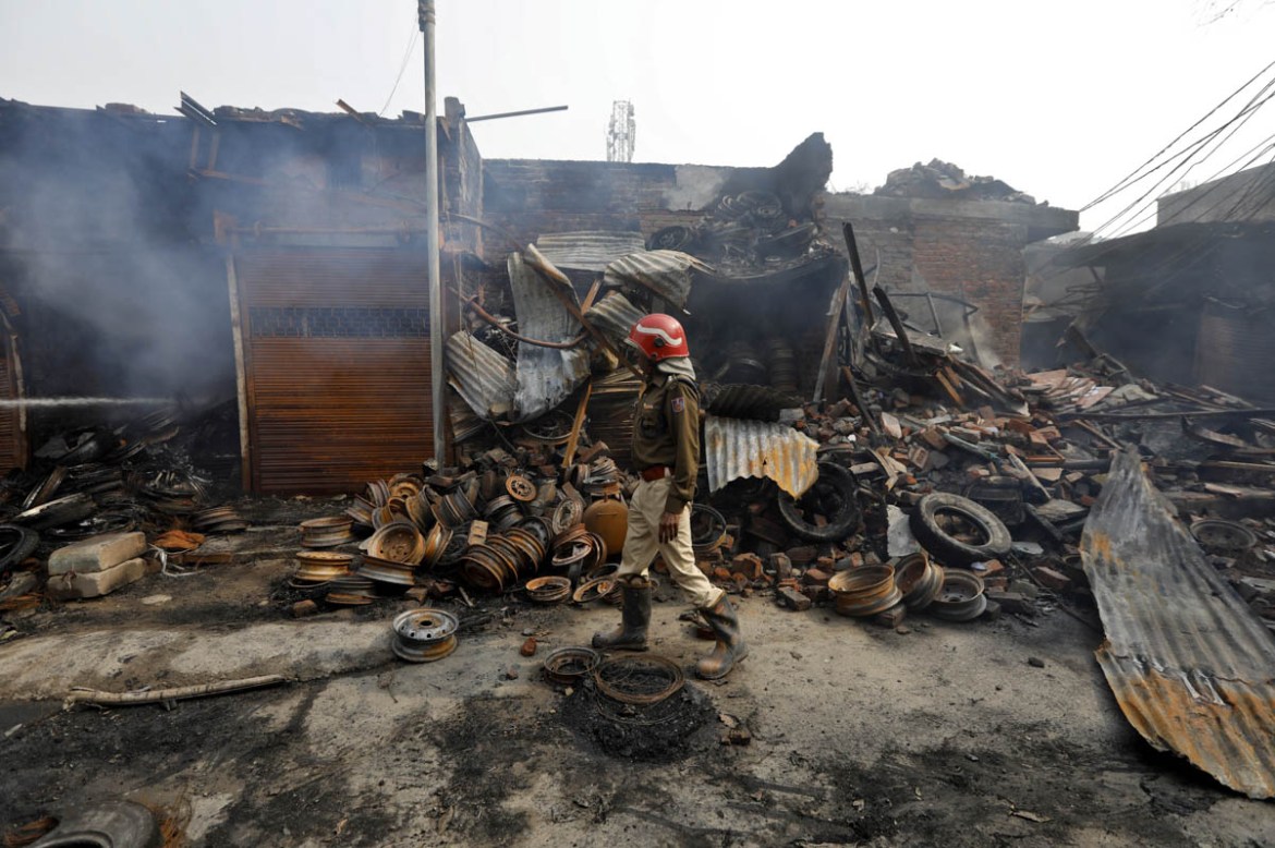 A firefighter walks past damaged shops at a tyre market after they were set on fire by a mob in a riot affected area after clashes erupted between people demonstrating for and against a new citizenshi