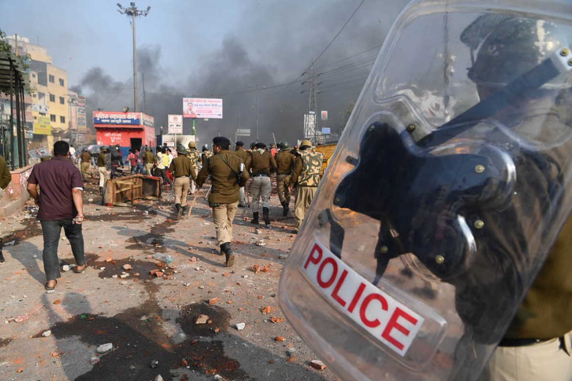 Riot police walk along a road scattered with stones following clashes between supporters and opponents of a new citizenship law, at Bhajanpura area of New Delhi on February 24, 2020, ahead of US Presi