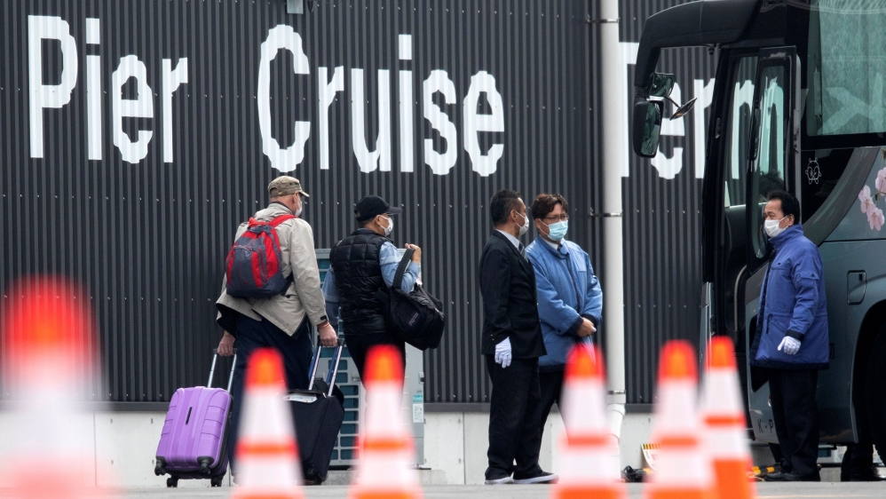 Passengers wearing masks leave the coronavirus-hit cruise ship Diamond Princess at Daikoku Pier Cruise Terminal in Yokohama