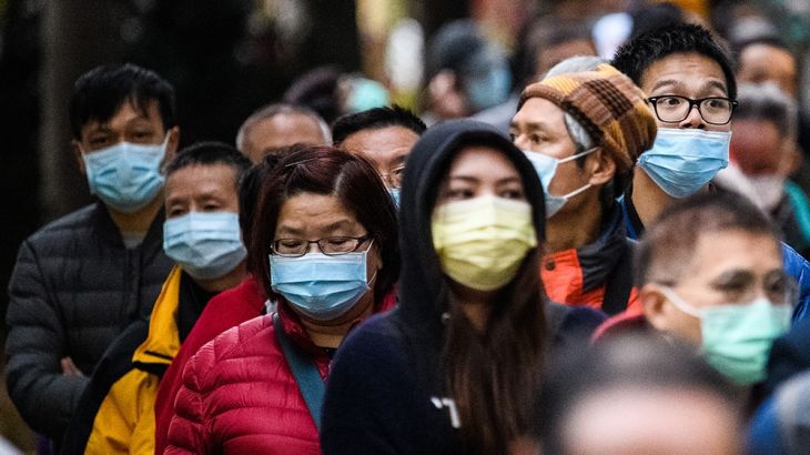 People wearing facemasks as a preventative measure following a coronavirus outbreak which began in the Chinese city of Wuhan, line up to purchase face masks from a makeshift stall after queueing for h