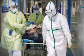 Medical workers in protective suits move a patient at an isolated ward of a hospital in Caidian district following an outbreak of the novel coronavirus in Wuhan