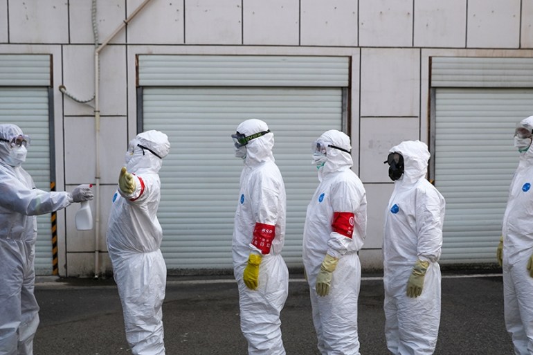 Volunteers in protective suits are being disinfected in a line in Wuhan, the epicentre of the novel coronavirus outbreak, in Hubei province, China February 22, 2020. Picture taken February 22, 2020. C