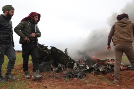 Syrian rebel fighters gather around the burning remains of a military helicopter after it was shot down over the village of Qaminas, about 6 kilometres southeast of Idlib city in northwestern Syria on