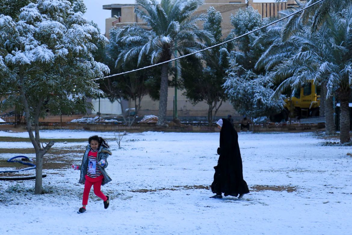 An Iraqi girl plays with her mother in the snow in the holy Shiite city of Karbala on February 11, 2020. - Iraq''s capital Baghdad woke up covered in a thin layer of fresh snow, an extremely rare pheno