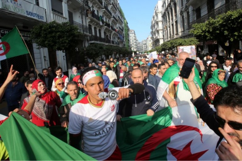 Demonstrators carry national flags as they march in Algiers