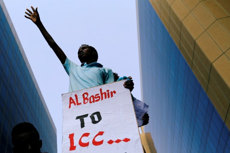 A protester holds a placard during a rally calling for a stop to killing in Darfur and stability for peace, next to a building in front of Ministry of Justice in Khartoum