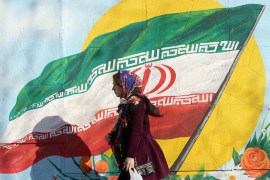 epa08213116 An Iranian woman walks next to a wall painting of Iranian national flag on a street of Tehran, Iran, 12 February 2020. Iranian candidates for the parliamentary elections will begin campaig
