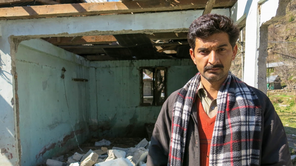 Muhammad Siddiq Mir, 30, stands amid the rubble of his home, destroyed by Indian artillery firing across the Line of Control into the Pakistan-administered Kashmir village of Jura. [Asad Hashim/Al Jaz