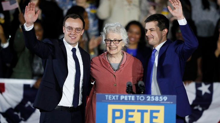 Democratic presidential candidate former South Bend, Ind., Mayor Pete Buttigieg, his mom Anne Montgomery and husband Chasten, left, wave to supporters at a caucus night campaign rally, Monday, Feb. 3,