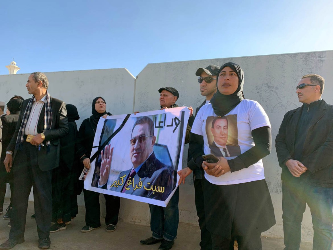 Supporters of former Egyptian President Hosni Mubarak hold his photos outside the main gate of Field Marshal Mohammed Hussein Tantawi Mosque, where his funeral will be held, east of Cairo, Egypt Febru
