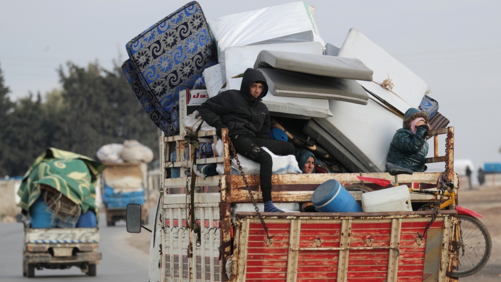 Internally displaced people ride on a pick up truck with their belongings in Azaz