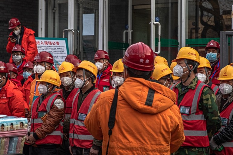 epa08202429 Construction workers wearing protective face masks stand on a street in Beijing, China, 08 February 2020. The novel coronavirus (2019-nCoV), which originated in the Chinese city of Wuhan,