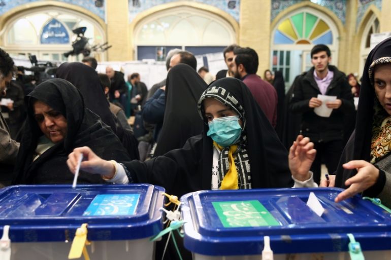Woman wears a face mask as she casts her vote during parliamentary elections at a polling station in Tehran