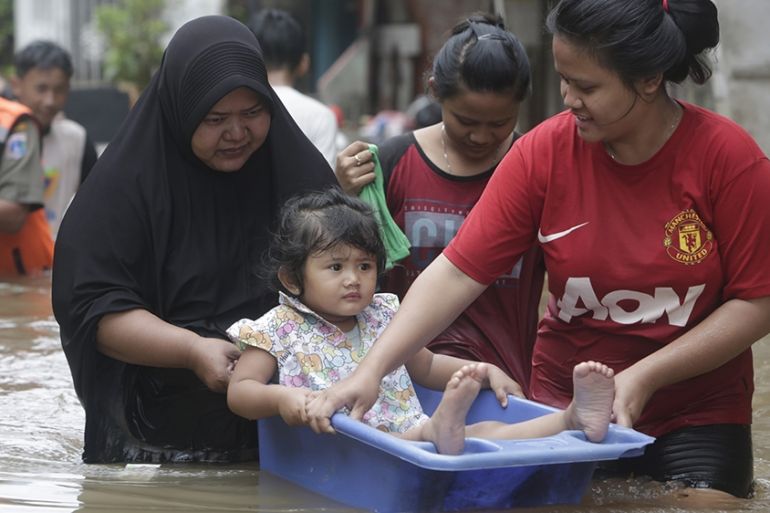 Resident carry a young girl as they walk in a flooded street in Jakarta, Indonesia, 25 February 2020. According the National Disaster Management Authority (BNPB), heavy rains triggered widespread flo